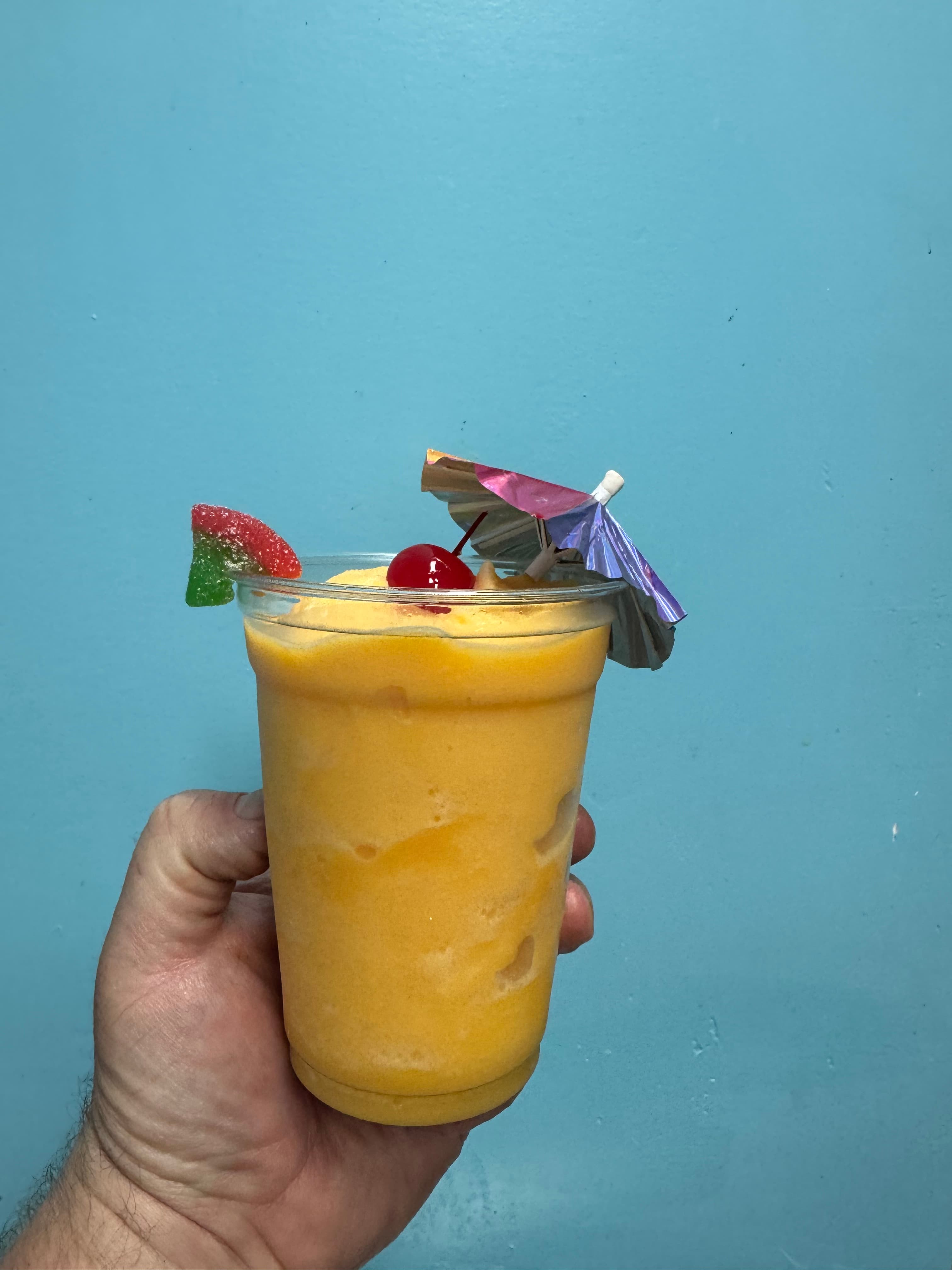 Mango margarita Dole mocktail topped with a cherry and a mini umbrella
